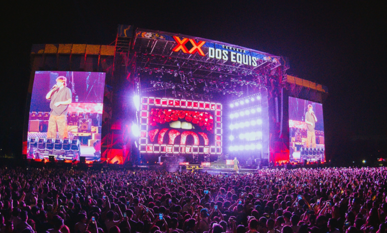 Nighttime outdoor concert with a huge illuminated stage and a dense crowd watching a performance.